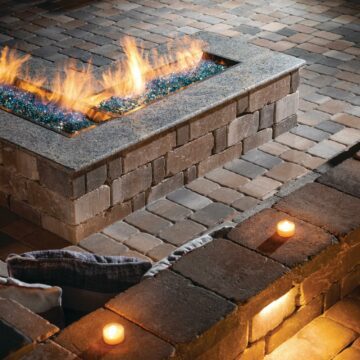 built-in L-shaped cobbled paver patio with custom fire table