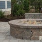 Gas circle firepit with a kneecap wall for sitting.