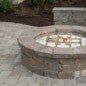 Gas circle firepit with a kneecap wall for sitting.