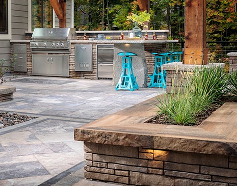 Outdoor kitchen with grill island kit installed with background patio pavers