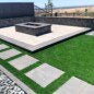 Paver patio and synthetic turf combo with a retaining wall in the background