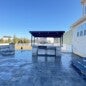 Outdoor kitchen installation with custom-built wood-burning grill, overhead cedar beams, stone fire pit, integrated bench seating, and happy client enjoying the finished space. 📄 Description
