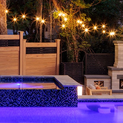 Outdoor living space with accent lighting and pool features by Belgard.