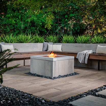Outdoor living space featuring a fire feature that is lit. Two benches around it
